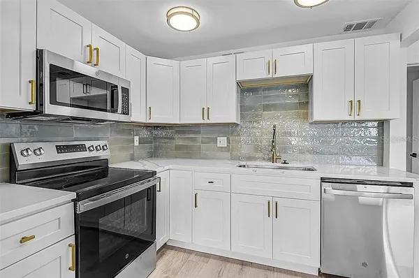 a kitchen with white cabinets and appliances