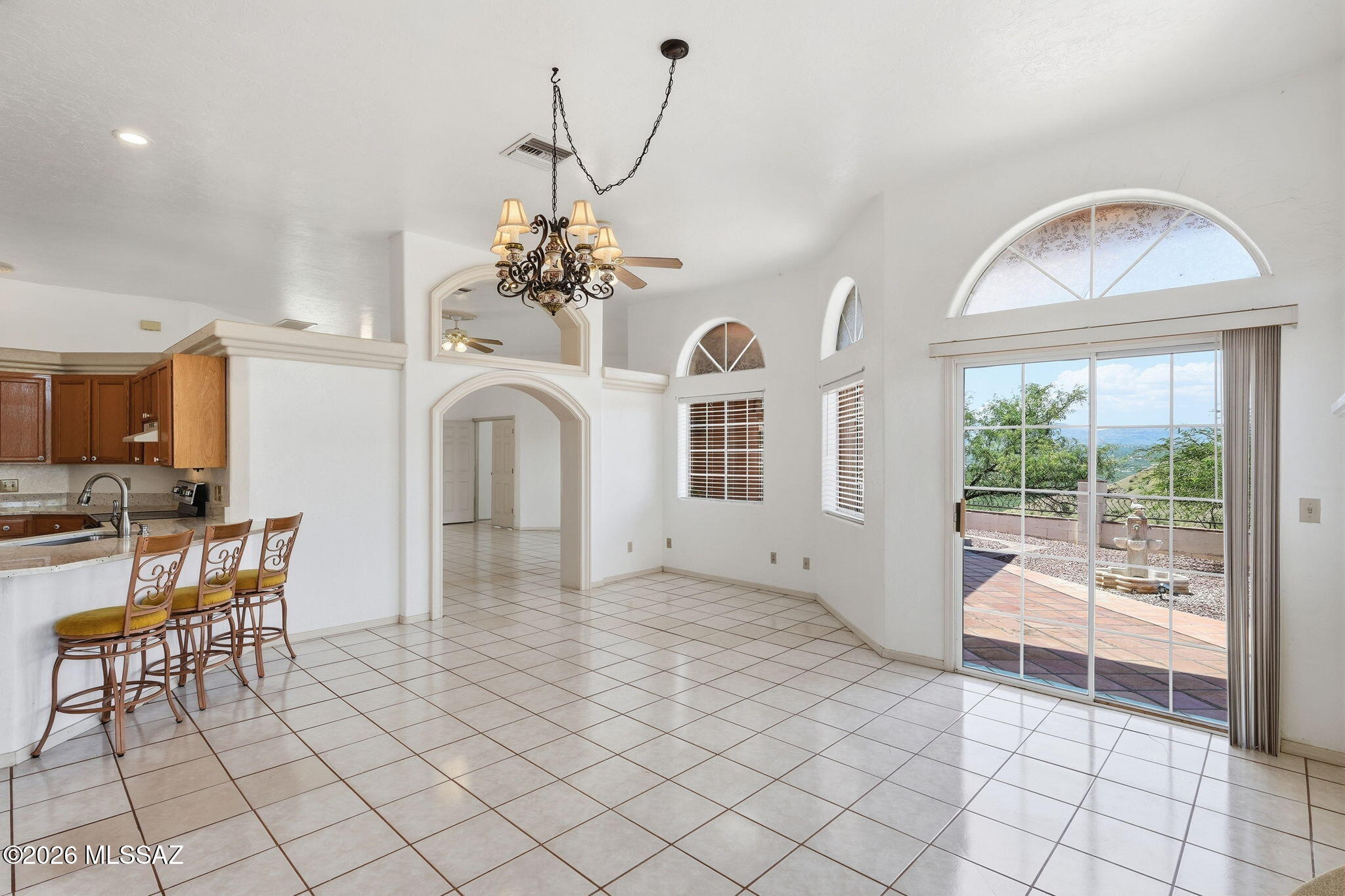 1242 Vista Court Rio Rico, AZ 85648 - Photo 10 of 51 Multiple access points to the backyard make indoor-outdoor living easy, including these large sliding glass doors located just off the living room. An arched window above the doors adds architectural character while allowing even more natural light to fill the space and creating a stylish transition to the outdoor living areas.