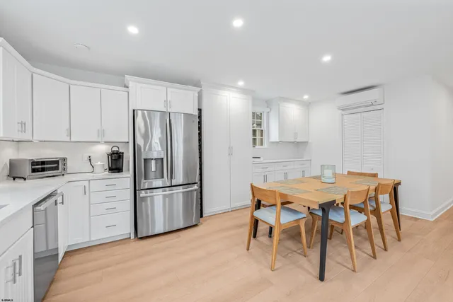 a kitchen with stainless steel appliances kitchen island granite countertop a dining table chairs and refrigerator