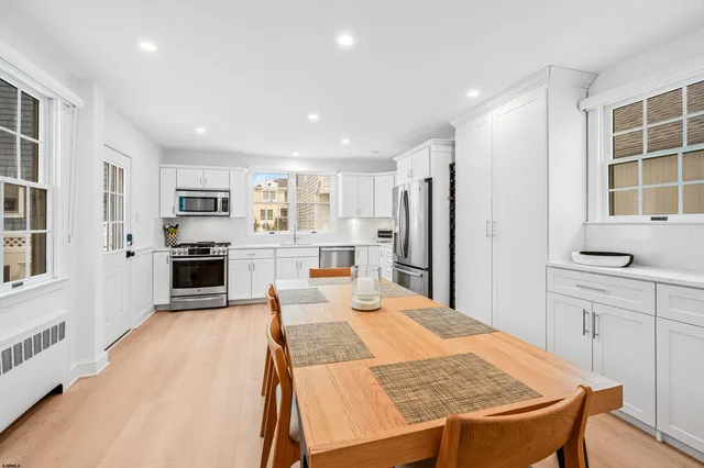 a large kitchen with kitchen island a stove a sink a refrigerator and white cabinets with wooden floor