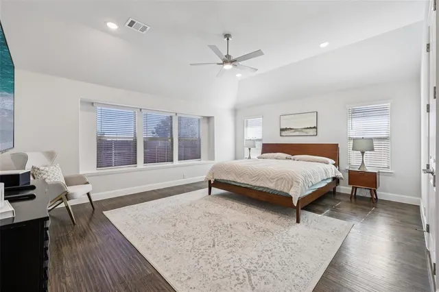 a bedroom with a large bed a chandelier and windows