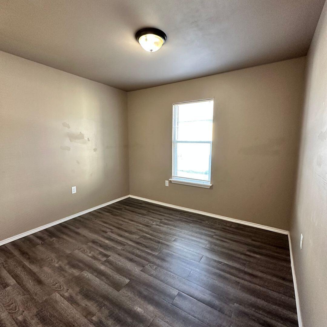 113 36th Street, Unit 2 Lubbock, TX 79404 - Photo 7 of 8 an empty room with wooden floor and windows