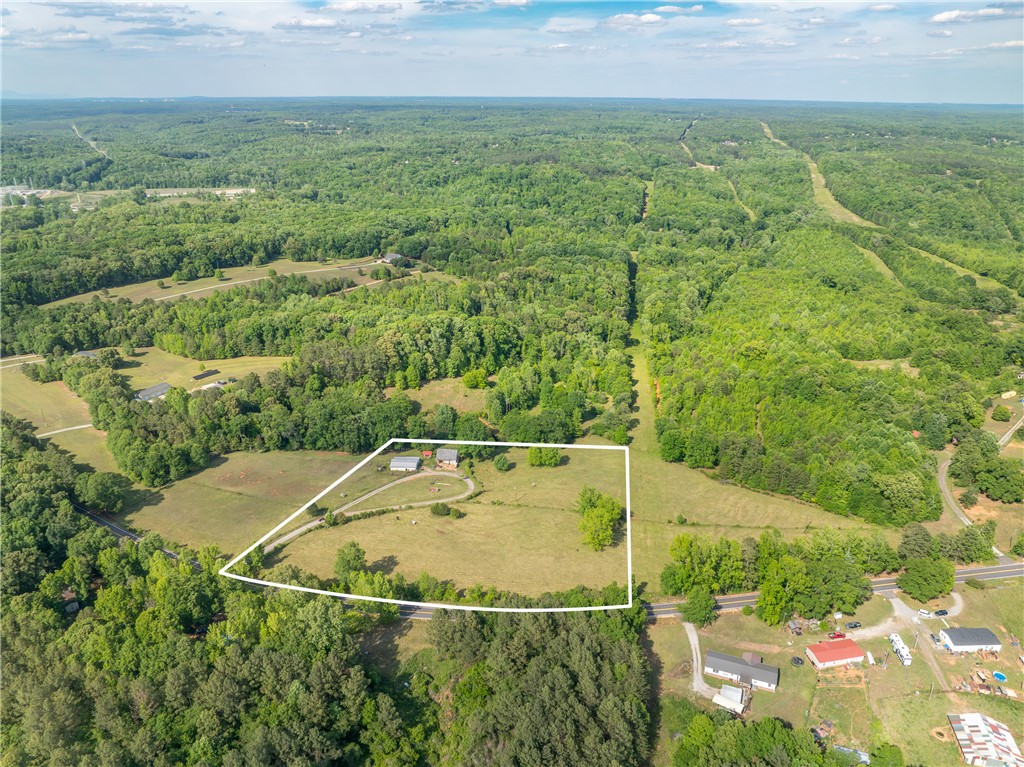 This expansive aerial view showcases a vast, verdant landscape with scattered homes and winding roads.