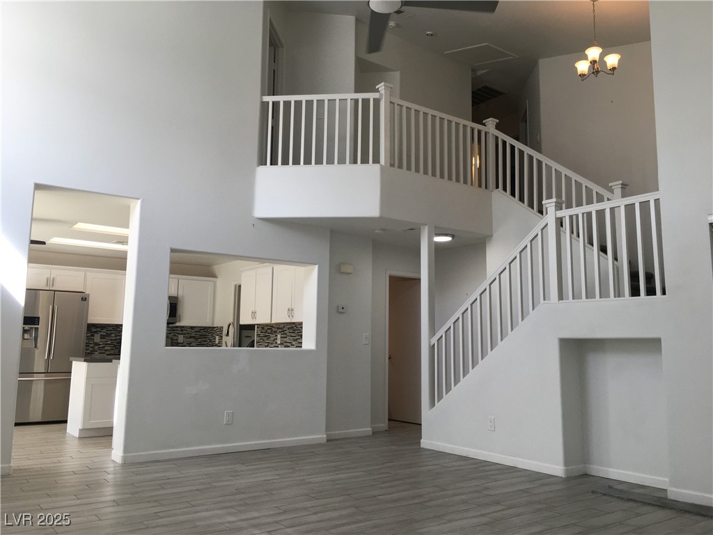973 Cedar Pines Street Henderson, NV 89011 - Photo 3 of 37 Unfurnished living room with a towering ceiling, light wood-style floors, stairs, and a chandelier