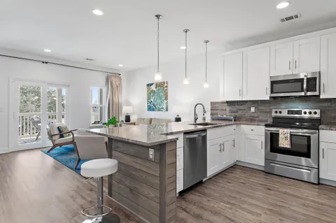 a kitchen with stainless steel appliances granite countertop a stove a sink a microwave a center island and furniture