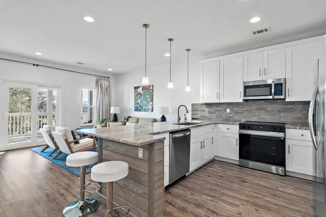 a open kitchen with stainless steel appliances granite countertop a stove top oven a sink dishwasher a dining table and chairs with wooden floor