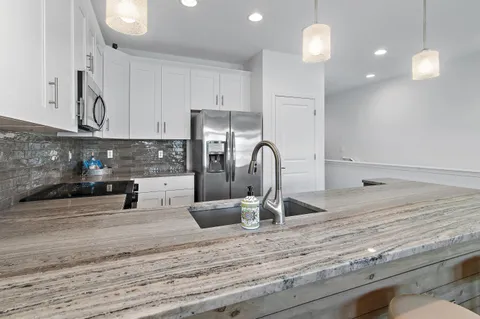 a kitchen with stainless steel appliances granite countertop a sink a stove and a refrigerator