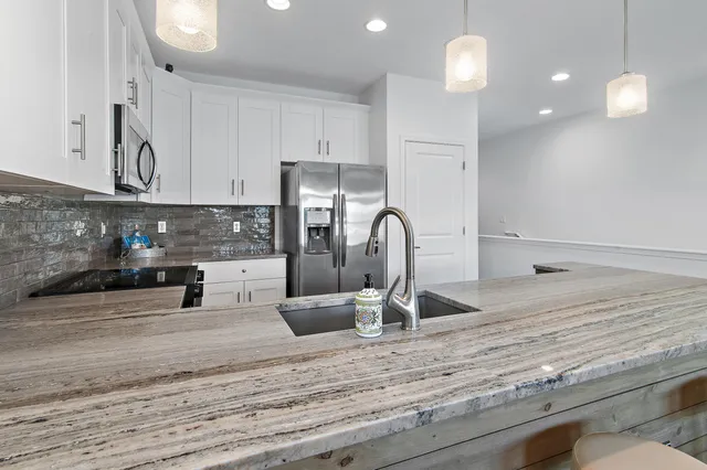 a kitchen with stainless steel appliances granite countertop a sink a stove and a refrigerator