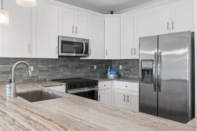 a kitchen with stainless steel appliances kitchen island a white cabinets sink and a granite counter top