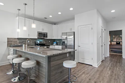 a kitchen with stainless steel appliances granite countertop a stove a refrigerator a kitchen island a sink cabinets and wooden floor