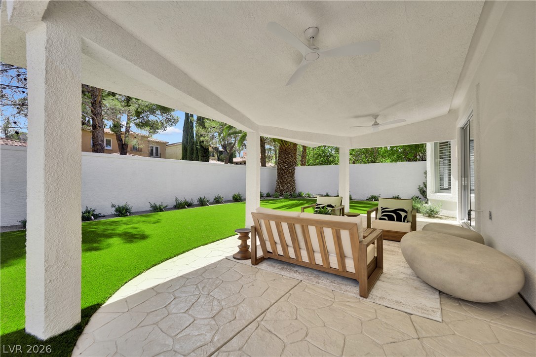 8981 Rivers Edge Drive Las Vegas, NV 89117 - Photo 50 of 69 An inviting covered patio with textured flooring opens to a vibrant green yard, perfect for outdoor relaxation.