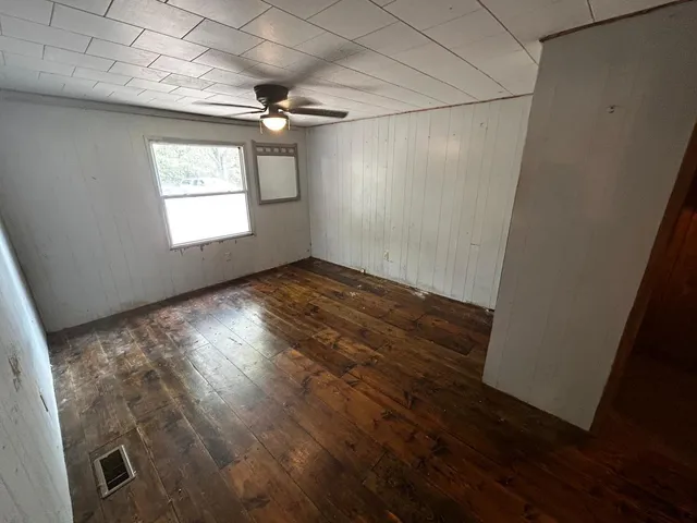 an empty room with wooden floor cabinet and windows