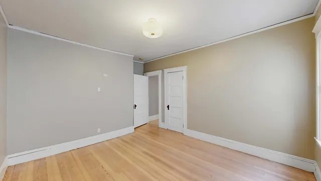 a view of an empty room with chandelier fan and wooden floor