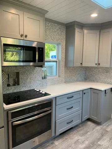 a kitchen with granite countertop white cabinets and stainless steel appliances