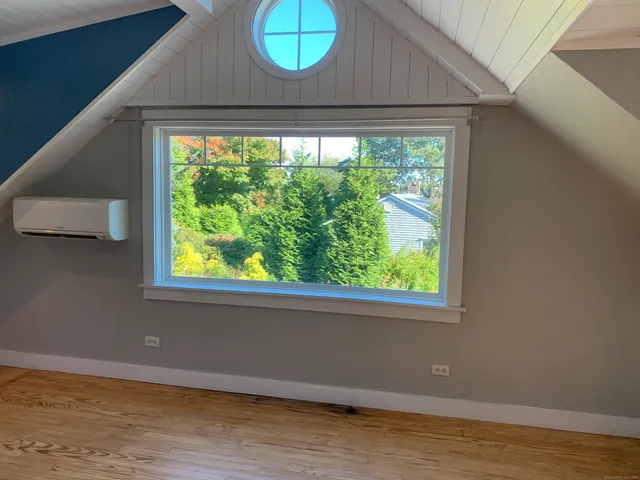 a view of empty room with wooden floor and a large window