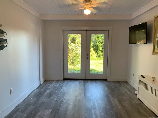 an empty room with wooden floor fan and windows