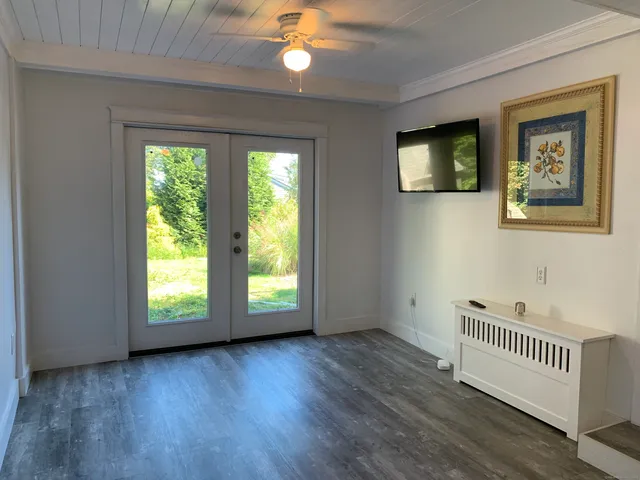 a view of an empty room with a window and wooden floor