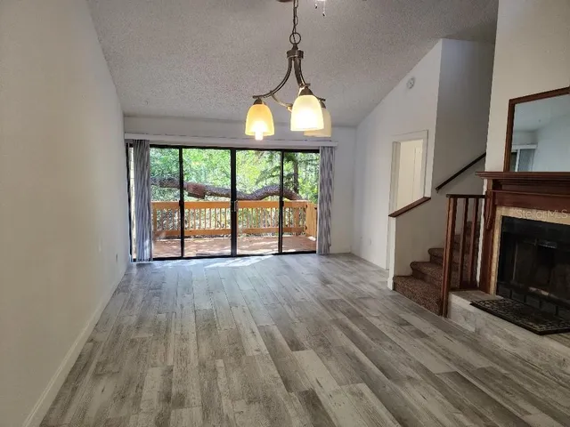 an empty room with wooden floor fireplace and windows