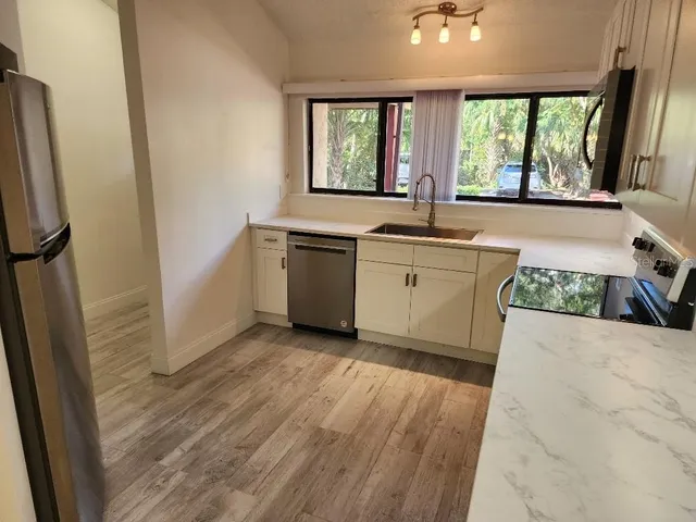 a large kitchen with a sink and dishwasher a stove top oven with wooden floor