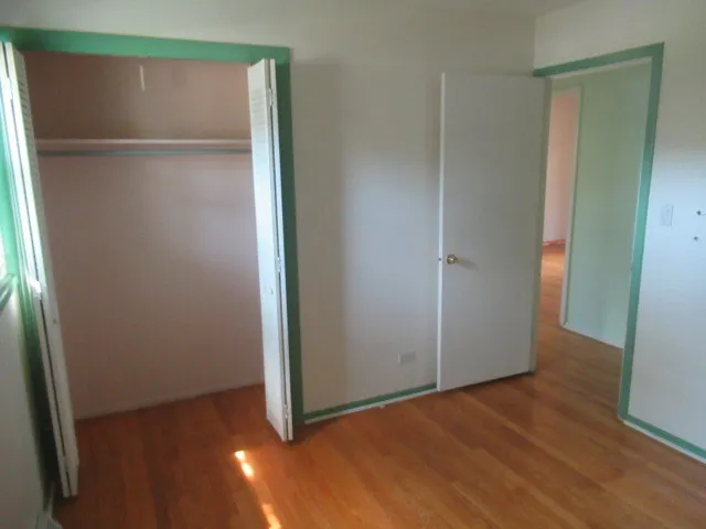 an empty room with wooden floor and closet