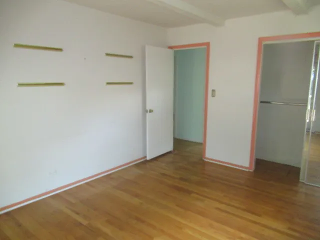 an empty room with wooden floor and closet