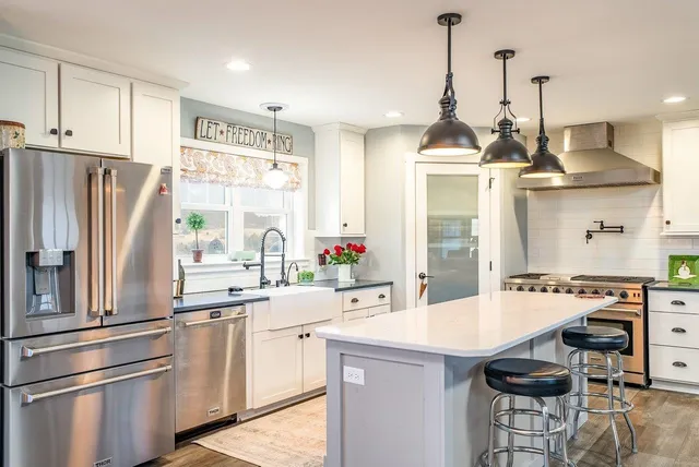 a open kitchen with stainless steel appliances granite countertop a sink a stove a dining table and chairs