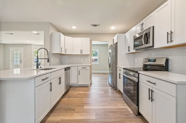 a kitchen with stainless steel appliances granite countertop a stove top oven a sink dishwasher and a refrigerator with wooden cabinets