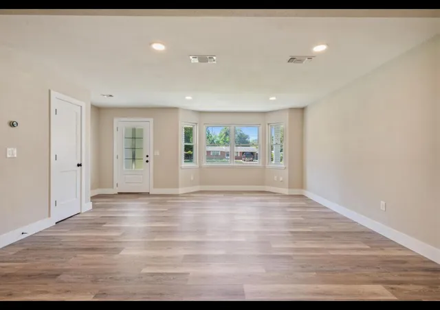 a view of an empty room with window and wooden floor