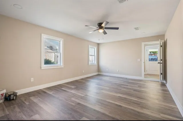 a view of empty room with wooden floor and fan