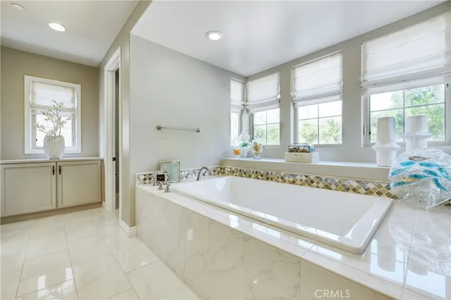 a spacious bathroom with a tub a sink and mirror