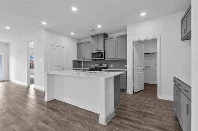 a kitchen with kitchen island a sink stainless steel appliances and cabinets