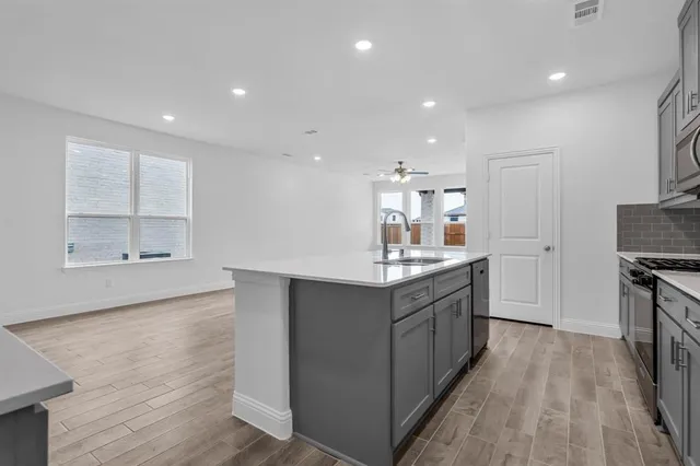 a large kitchen with stainless steel appliances a large counter top a stove a sink and a refrigerator