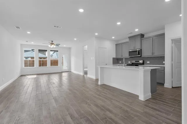 a view of kitchen with granite countertop stainless steel appliances refrigerator sink and cabinets