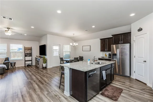 a large kitchen with stainless steel appliances granite countertop a lot of counter space and wooden floor
