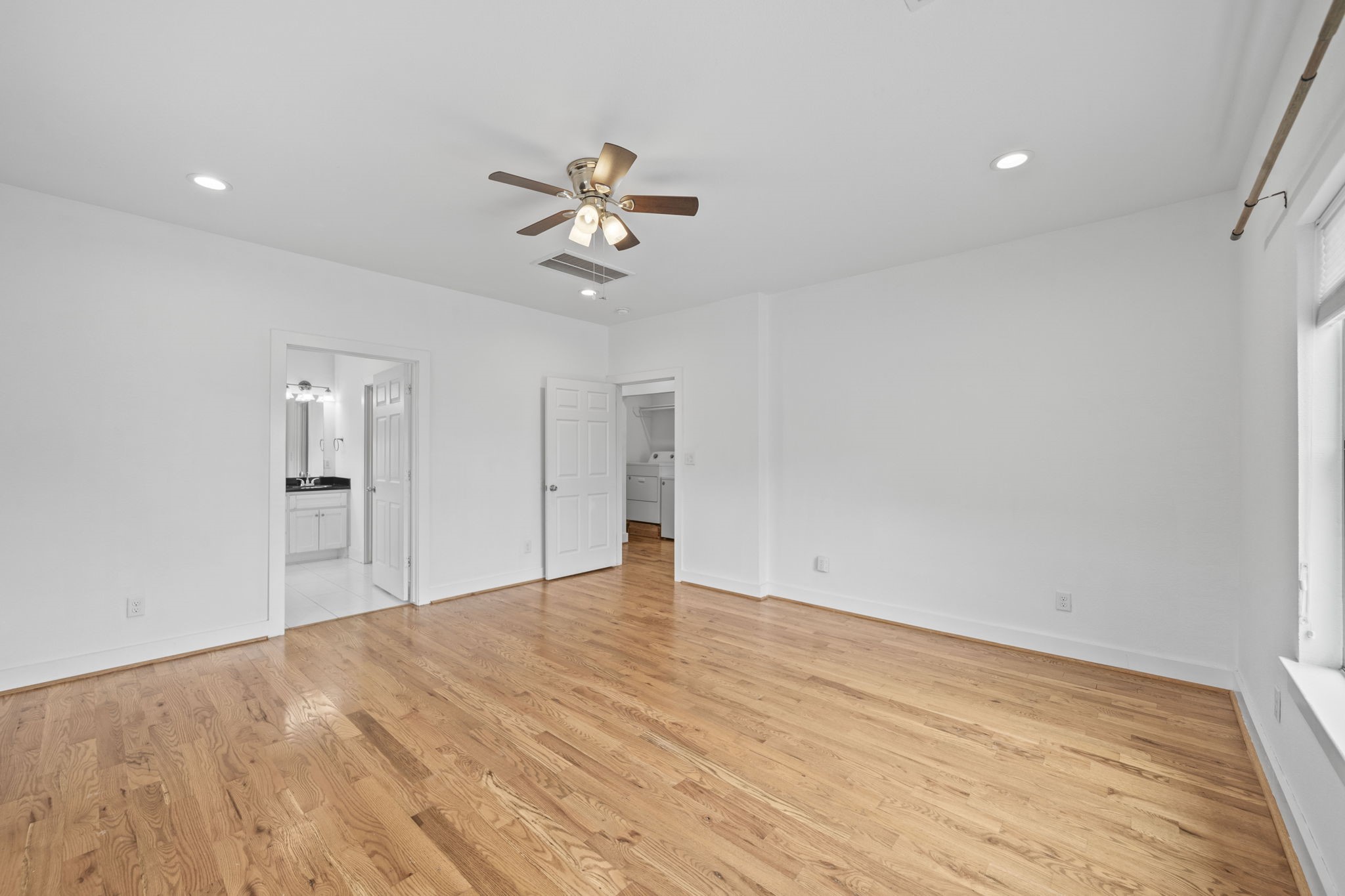 4734 Bell Street, Unit B Houston, TX 77023 - Photo 6 of 10 Large bedroom or flexible living space with wood flooring, recessed lighting, ceiling fan, nearby bath access, and laundry access visible beyond.