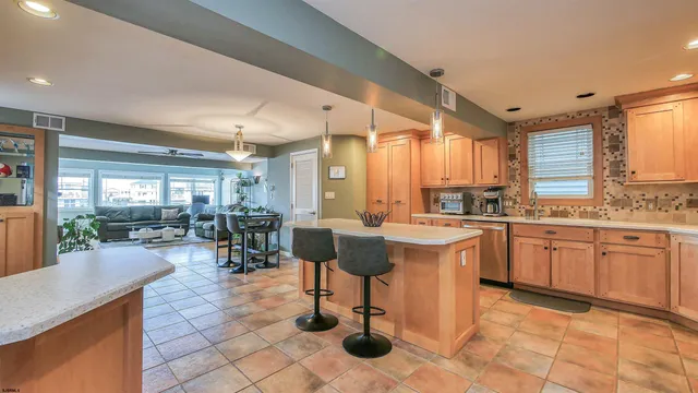 a open kitchen with stainless steel appliances kitchen island granite countertop a refrigerator oven a sink a dining table and chairs with wooden floor