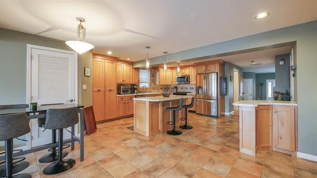a kitchen with refrigerator a sink and chairs