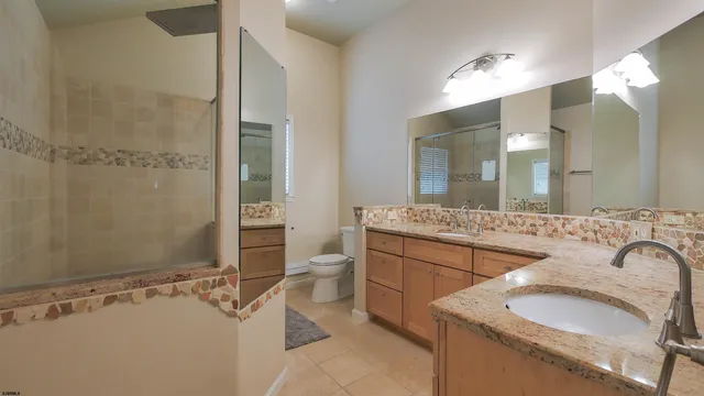 a bathroom with a granite countertop sink a mirror and a shower