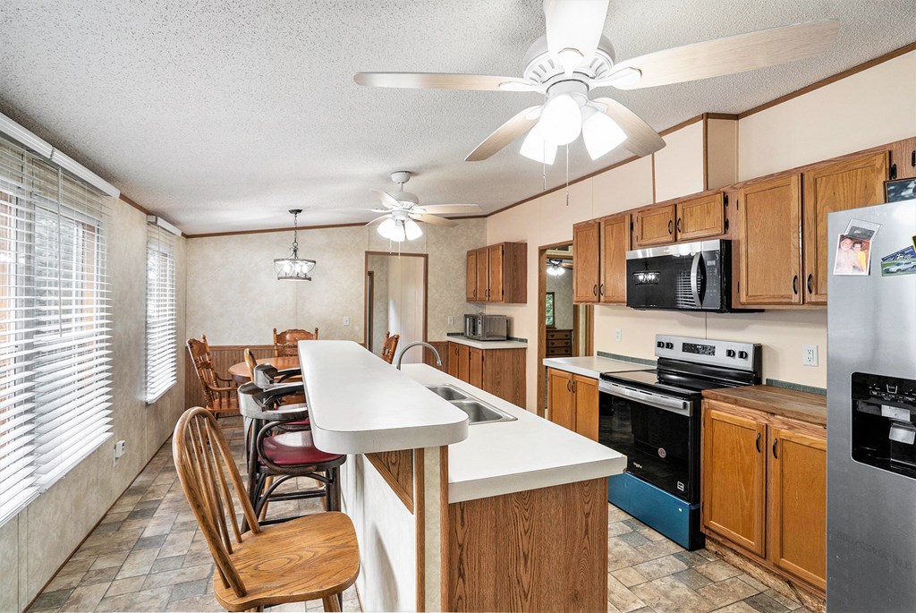 359 Norton Bridge Road Chatsworth, GA 30705 - Photo 7 of 28 a kitchen with stainless steel appliances kitchen island granite countertop a stove top oven a sink a dining table and chairs with wooden floor