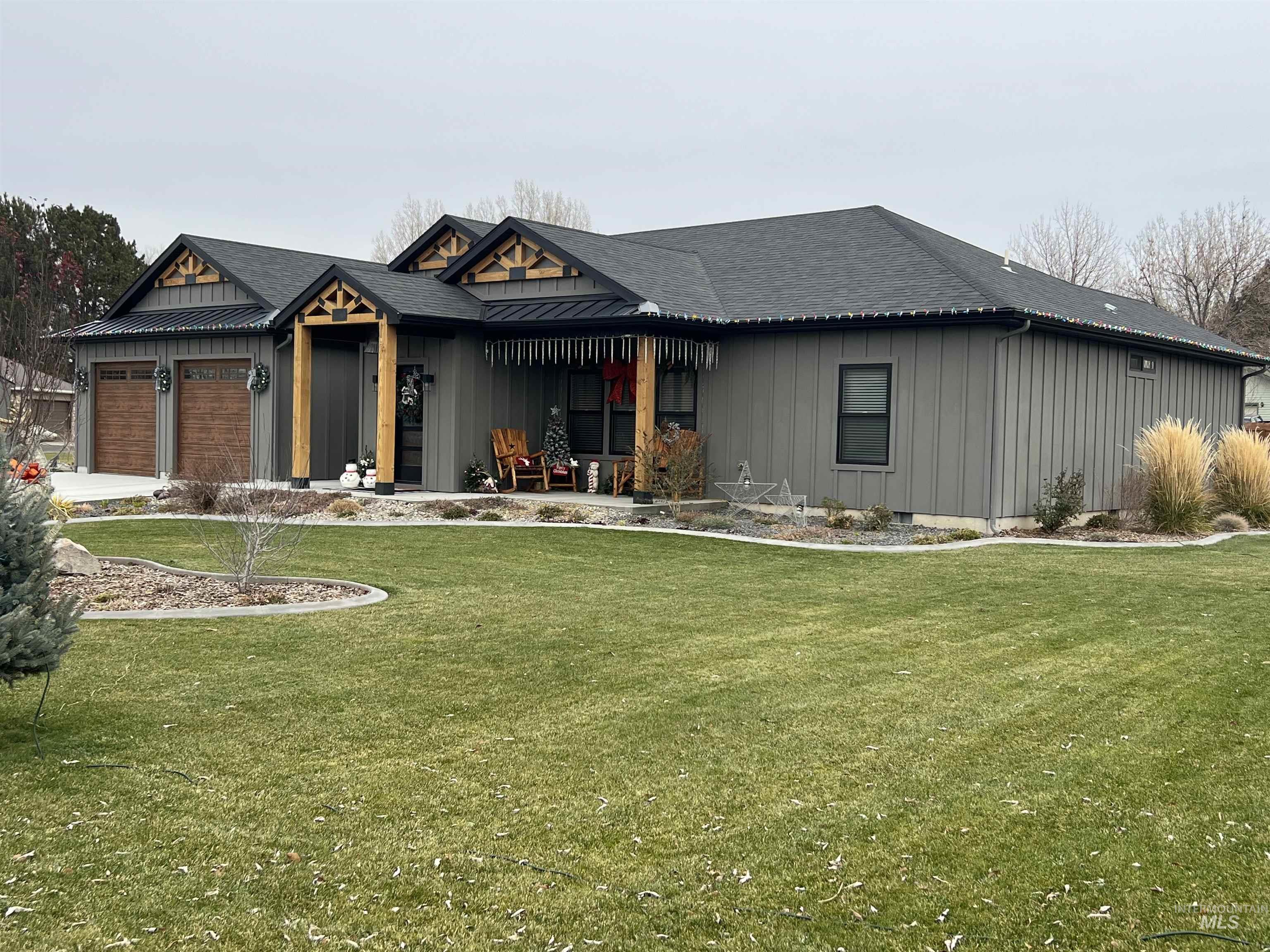 View of front of house featuring covered porch, a shingled roof, board and batten siding, and a front yard