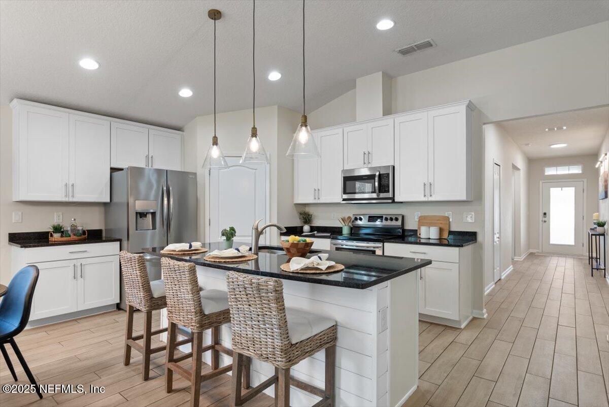 88 North Hamilton Springs Road St. Augustine, FL 32084 - Photo 17 of 73 a kitchen with stainless steel appliances granite countertop a stove a sink a microwave a refrigerator and white cabinets with wooden floor