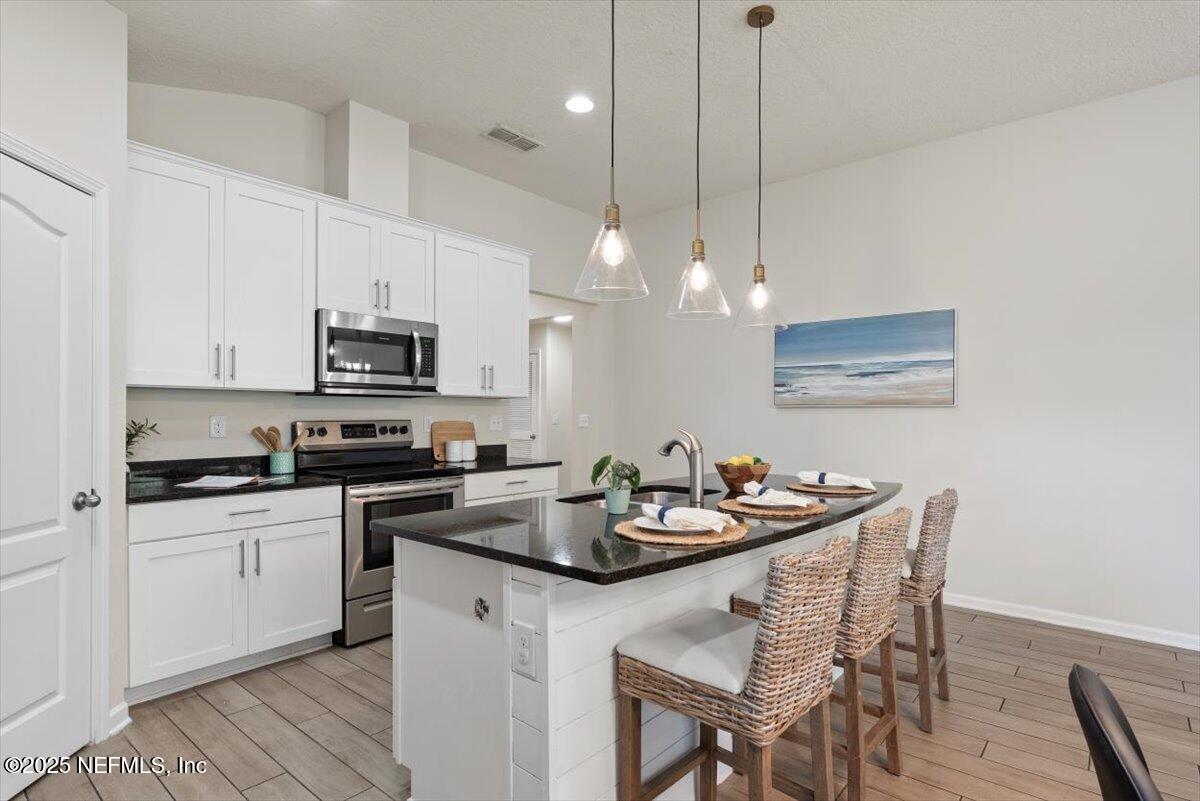 88 North Hamilton Springs Road St. Augustine, FL 32084 - Photo 18 of 73 a kitchen with stainless steel appliances kitchen island granite countertop a sink a stove a microwave a dining table and chairs