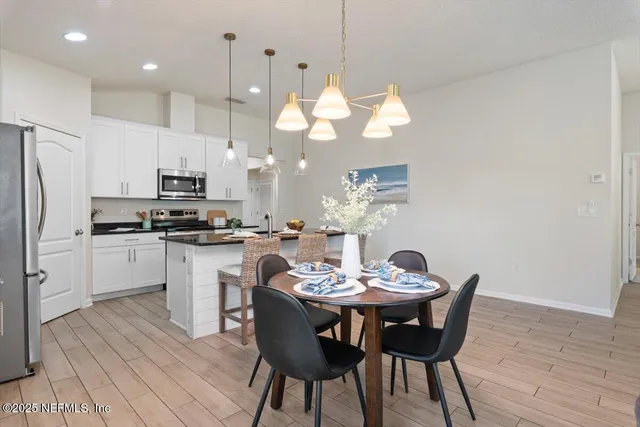 a living room with furniture kitchen view and a chandelier
