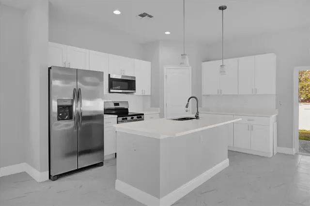 a kitchen with stainless steel appliances a refrigerator sink and white cabinets
