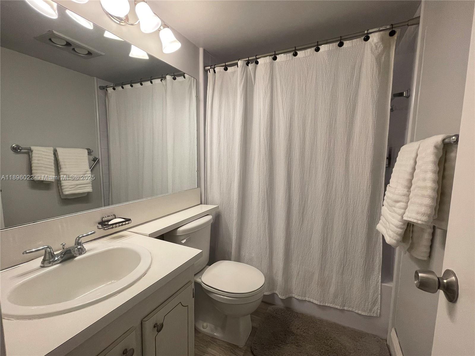 279 Markham M, Unit M Deerfield Beach, FL 33442 - Photo 14 of 15 a bathroom with a sink a toilet and shower curtain