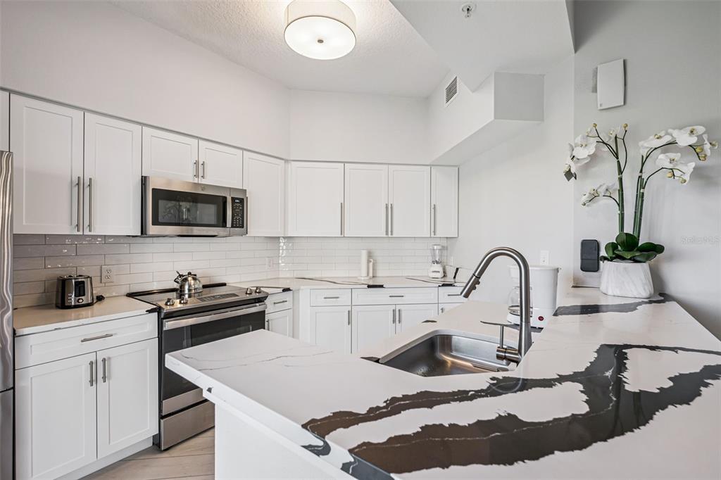 8774 Worldquest Boulevard, Unit 7307 Orlando, FL 32821 - Photo 14 of 52 a kitchen with a sink a stove and cabinets
