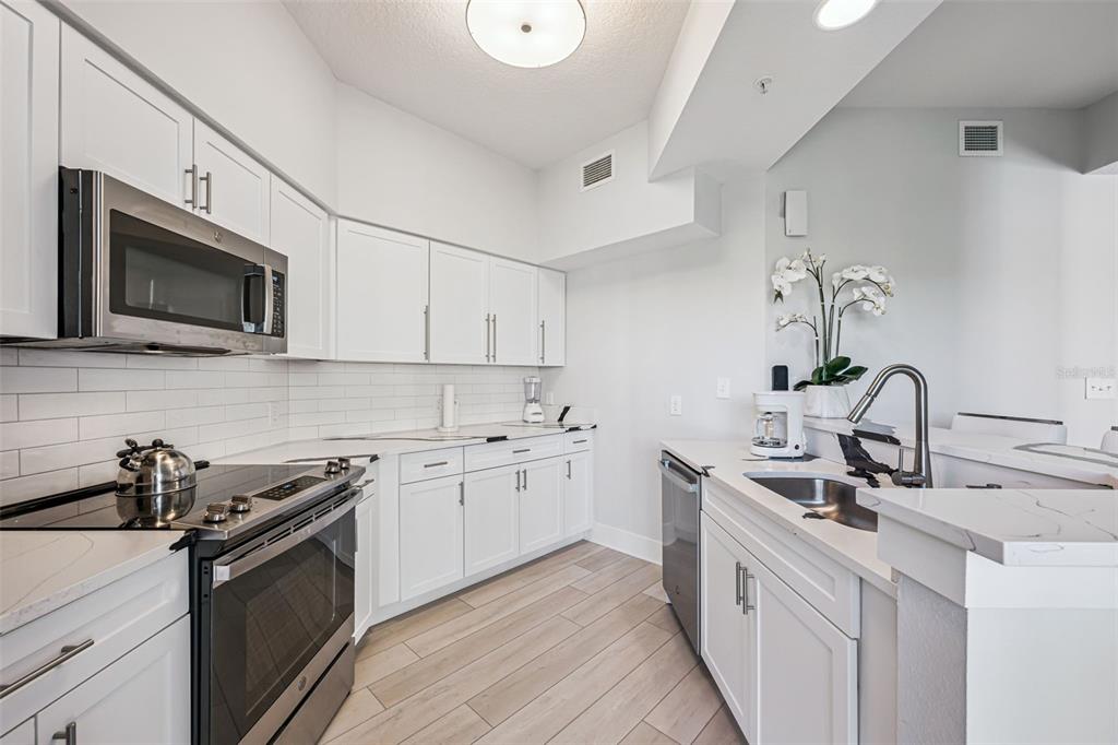 8774 Worldquest Boulevard, Unit 7307 Orlando, FL 32821 - Photo 15 of 52 a kitchen with stainless steel appliances granite countertop a sink stove microwave and refrigerator