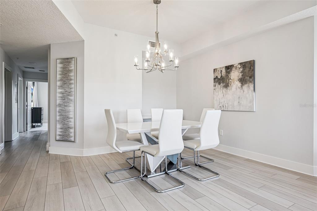 8774 Worldquest Boulevard, Unit 7307 Orlando, FL 32821 - Photo 9 of 52 a dining room with wooden floor a chandelier a glass table and chairs