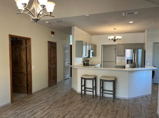 a kitchen with stainless steel appliances a dining table chairs and wooden floor