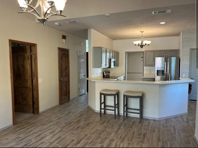 a large living room with stainless steel appliances kitchen island a chandelier
